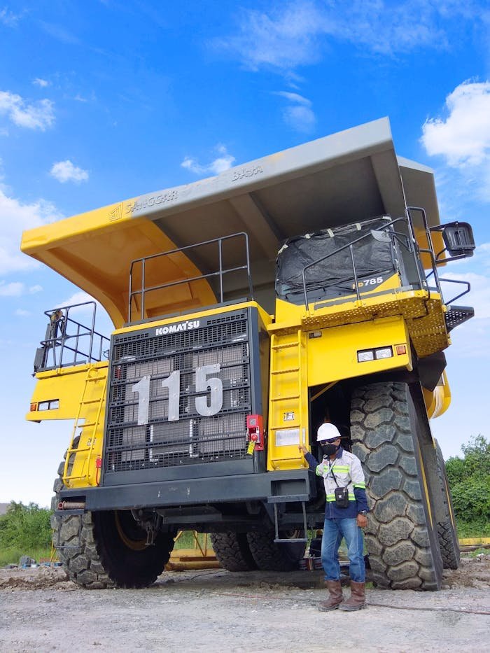 A large Komatsu mining truck with a worker standing beside it in Indonesia.