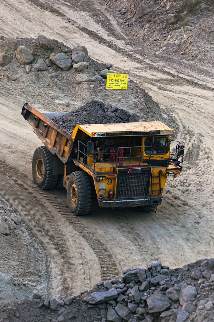Heavy mining truck transporting minerals in a rocky open-pit quarry in Bahula, West Bengal.